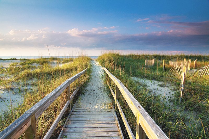 Calabash, NC beach access boardwalk leading through dunes to the ocean under a partly cloudy sky