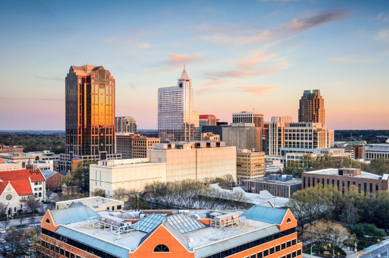 Skyline of downtown Raleigh, North Carolina featuring modern office buildings and cityscape at sunset.